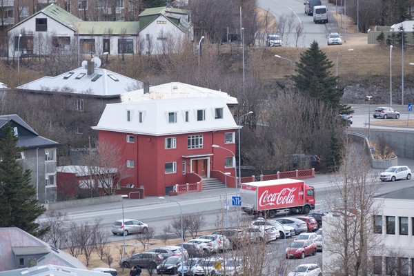 Red Coca-cola truck drives in front of red house